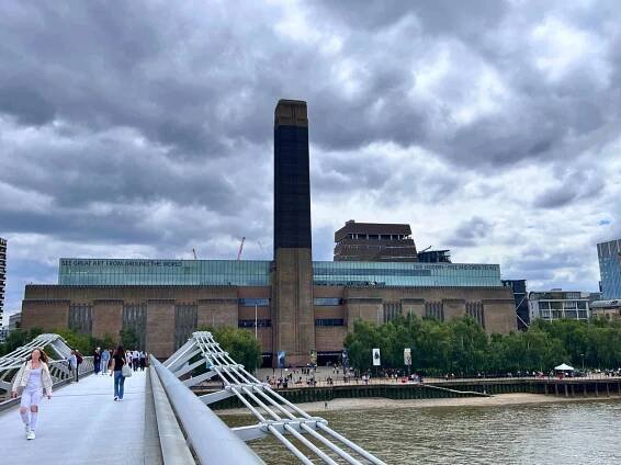Tate Modern Gallery - a red brick building with a tall central tower and an upper level on the main building with glass windows