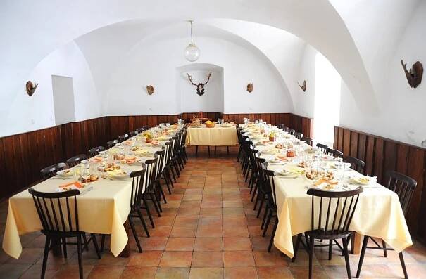 a long row of tables in a room with chairs at Penzion Zámek Rozsochatec in Rozsochatec