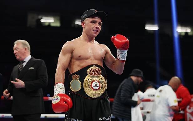 Nick Ball celebrates a boxing victory, wearing a championship belt.