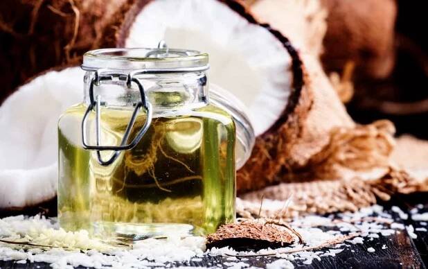 a class jar with coconut oil in with coconut in the background