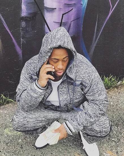 A man sitting on the ground talking on his cell phone.