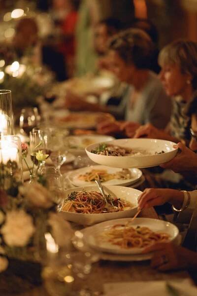 Guests Enjoying Pasta Dinner at Wedding Reception Illuminated by Candles