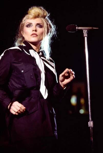 Debbie Harry on stage wearing a black '80s outfit