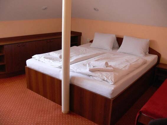a large bed with white sheets and pillows on it at Penzion Oaza in Luhačovice