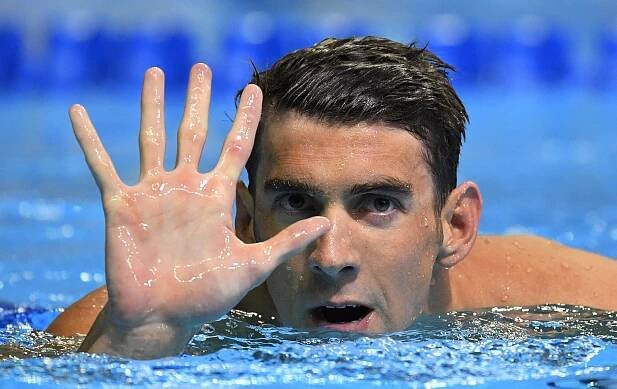 Fotookienko: Americký plavec Michael Phelps ukazuje na prstoch ruky číslo päť....