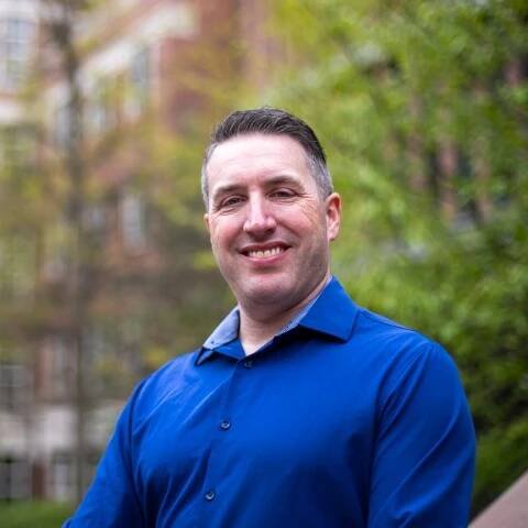 Brian Goodman MC/MPA 2024 wearing a sapphire blue sweater.