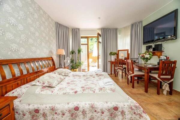 1 Schlafzimmer mit einem großen Bett und einem Esszimmer in der Unterkunft Penzion Sonáta in Luhačovice