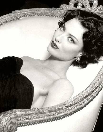 an old black and white photo of a woman in a dress on a couch with a tiara