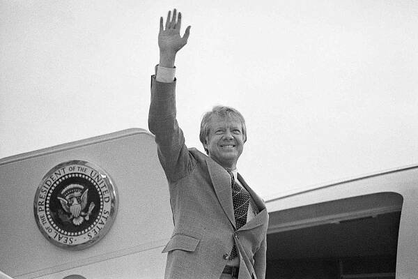 President Carter, shown waist-up, waves as he boards a helicopter on the White House lawn to fly to Camp David, Maryland, where he will spend the Thanskgiving holiday. He cancelled a holiday in Georgia because of the Iranian crisis.