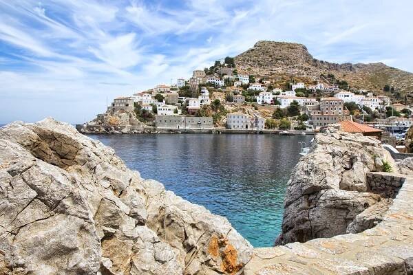 Photography from a rocky point next to the blue waters of the sea while in the background there are beautiful picturesque buildings