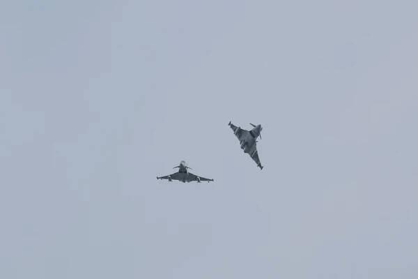 Two RAF Typhoons flying with one banking to the side.