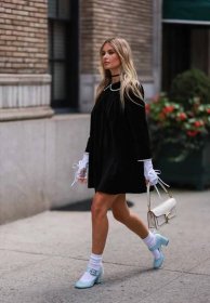 Xenia Adonts wears a black mini shift dress and gloves, a party outfit idea for 2023.