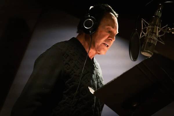 Wayne Newton standing in front of a microphone, recording vocals for the song 'This Is America' inspired by the 'Reagan' biopic
