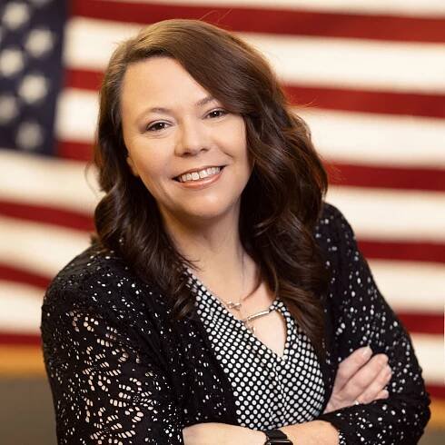 A woman is posing for a picture in front of an american flag.