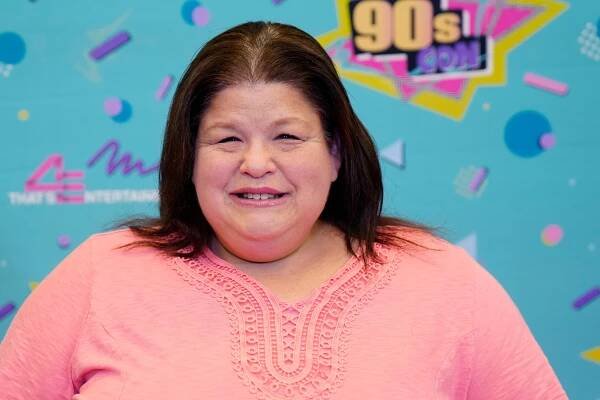 A woman in a pink shirt poses for the camera.
