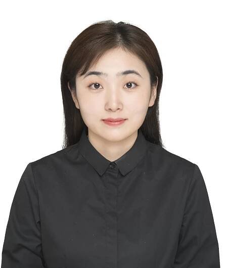 A woman standing in front of a white background wearing a black button-up shirt.