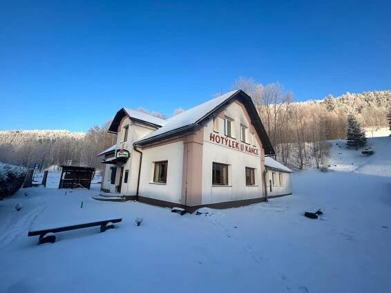 a building with a sign on it in the snow at Hotýlek u Kance in Lipova Lazne