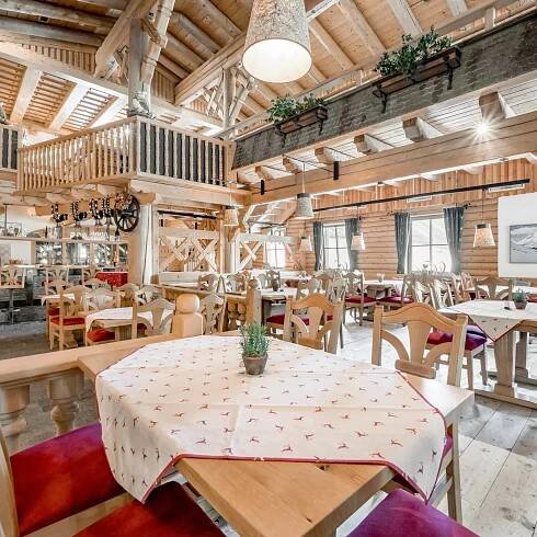 Heller Speisesaal im Alpenstil mit Holzdecke und roten Polsterstühlen