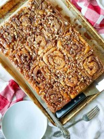 A pan of cinnamon rolls on a table with a checkered tablecloth.