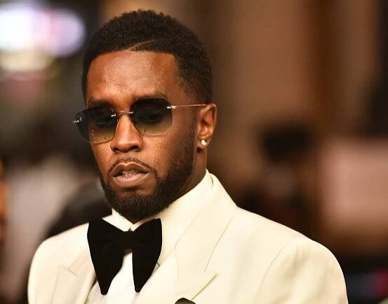 Sean 'Diddy' Combs wears a white tuxedo and sunglasses.