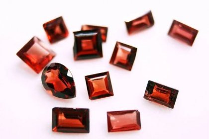 Twelve clear red faceted gemstones. One is oval, and the others are either rectangular or square.