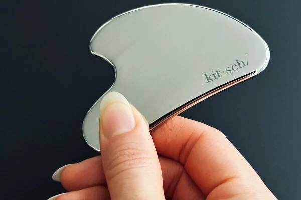 Close up of a person holding the Kitsch Stainless Steel Gua Sha Facial Tool
