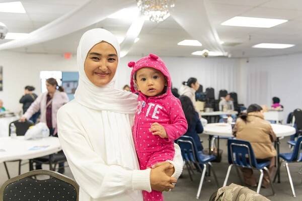 Hayrunisa Yenilmes, seen here with her infant child, and Amar Kilich of Alexandria are apprenticing Ajinur Setiwaldi and Subhinur Elemin of Arlington in Uyghur music traditions. The musicians gathered at the monthly bazaar held at the Uyghur Cultural Center in Fairfax to have a lesson on 2/1/25. 
Pat Jarrett/Virginia Humanities