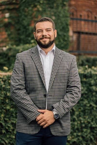 man outside in plaid blazer smiling 