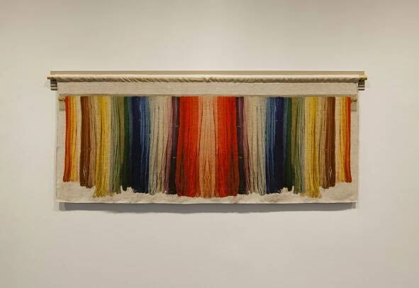 A colorful tapestry with mirrored colors that seem to be made of threads.