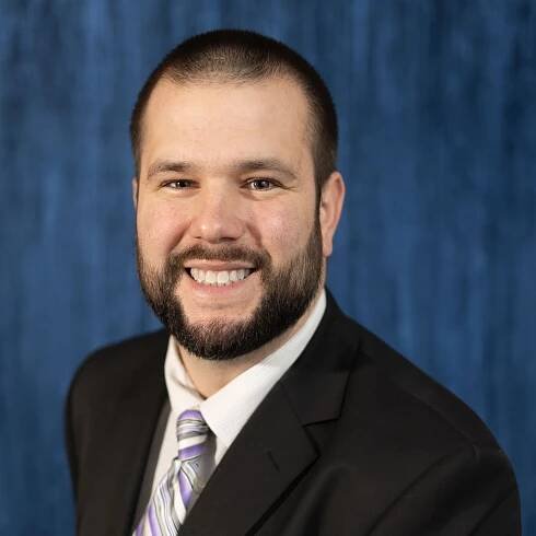 A man in a suit and tie is smiling for the camera
