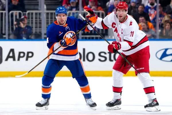 Tony DeAngelo (left) battles Jordan Staal for position during the Islanders' 3-2 overtime win over the Hurricanes on Jan. 25, 2025.
