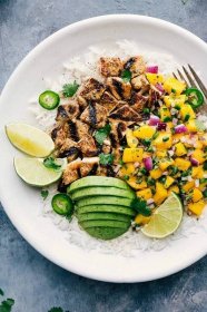 Mango Chicken is easy to throw together and mega flavorful! This delicious recipe starts with marinated chicken (either breast or thighs) and is topped with cilantro-lime mango salsa.   Recipe via Chelsea's Messy Apron #mango #chicken #avocado #grilled #dinner #easy