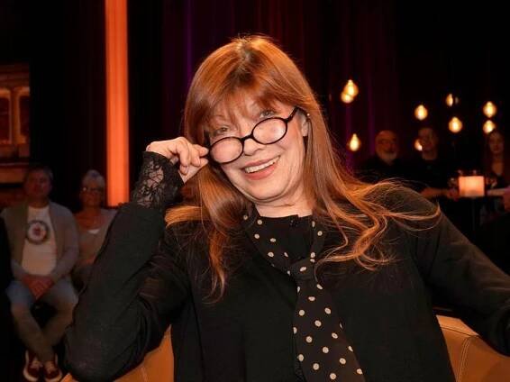 Die Sängerin und Schauspielerin Katja Ebstein schaut über den Rand ihrer Brille und lächelt in die Kamera.