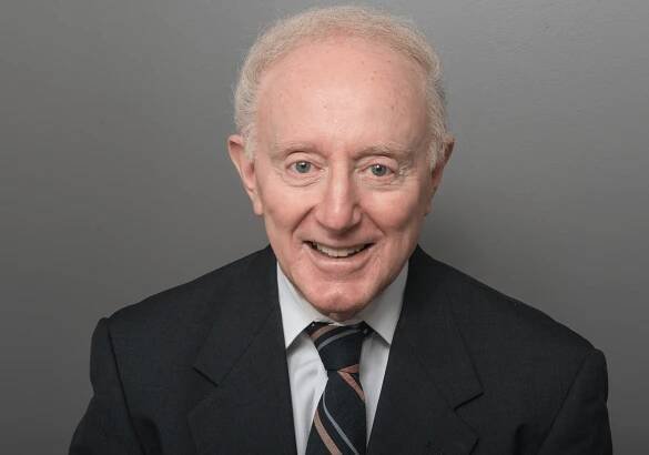 A formal portrait of Frank Protugal in a suit.