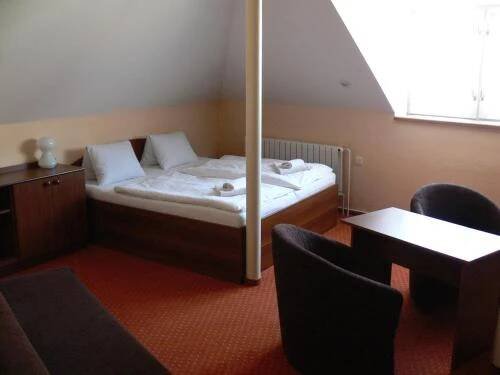 a bedroom with a bed with white sheets and pillows at Penzion Oaza in Luhačovice