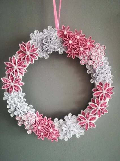 a pink and white wreath hanging on the wall