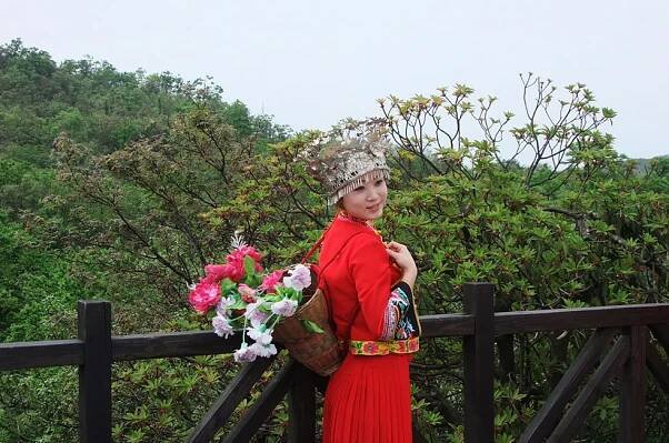 shutterstock_59180779 Hunan, A Hunan lady in traditional attire stand in front a beautiful mountain range