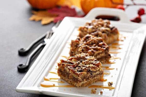 Closeup view of Pecan Pie Bars on a white plate drizzle in caramel sauce