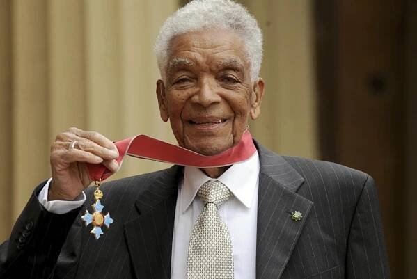 FILE - In this May 28, 2009 file photo, Earl Cameron poses for the media outside Buckingham Palace after being presented his CBE by Prince Charles, in London. Bermudian acting legend Earl Cameron has died, aged 102, it was announced Saturday, July 4, 2020. He was appointed a Commander of the Most Excellent Order of the British Empire in 2009 for his accomplishments, which included being the first black actor to star in a British feature film. (Anthony Devlin/PA via AP, file)