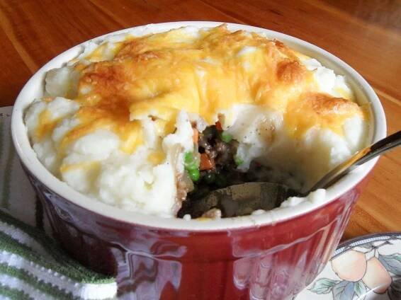 close up view of Shepherd's Pie in a red and white ramekin with a spoon