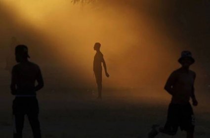 A man is seen in silhouette against evening sunlight.