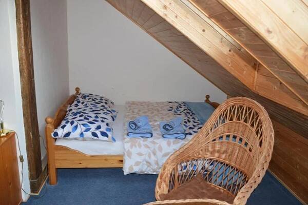 a bedroom with a bed and two wicker chairs at Penzion Krcma in Dolní Morava