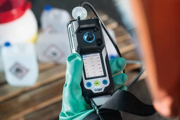 Průmyslový dělník kontroluje obrazovku přenosného detektoru plynů Dräger X-am 3500