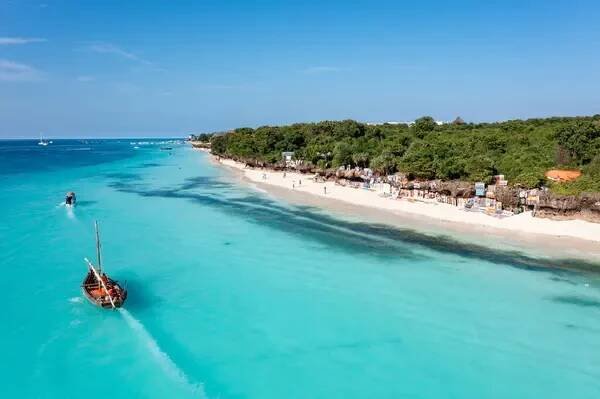 Zanzibar plážová scéna s dhow lodí a turistů těší tyrkysové vody. — Stock obrázek