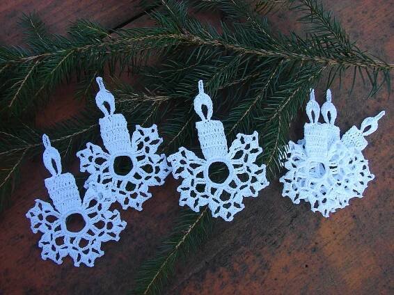three paper snowflakes are hanging from a pine tree branch on a table top