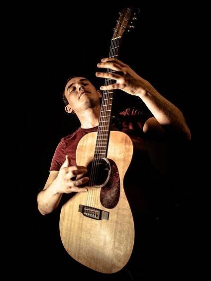 Chris Woods fingerstyle guitarist playing guitar in spot light