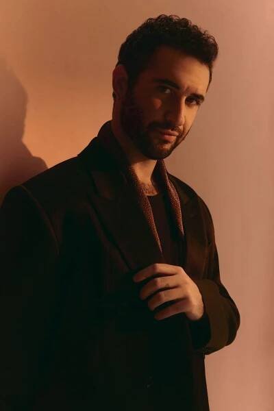Jordan Firstman in a black suit and red scarf