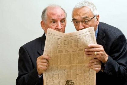 Two businessmen looking at the financial paper with surprised expression