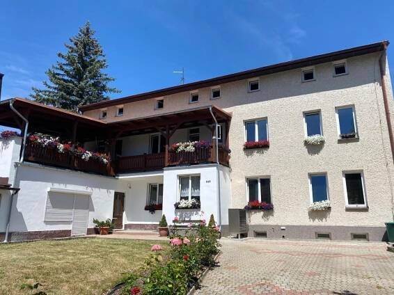 a large white building with a balcony and flowers at Penzion U Martina in Mariánské Lázně