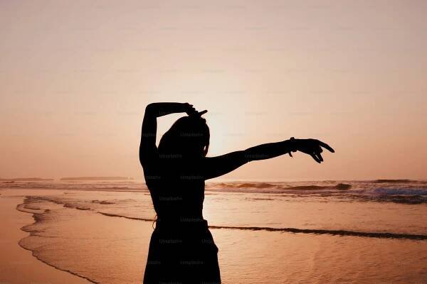 Silhouette of a dancer on a beach at sunset.